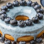 Blueberry Cheesecake Donut Cake 7 Blueberry Cheesecake Donut Cake with fresh blueberries and creamy cheesecake filling on top of a fluffy donut cake base.
