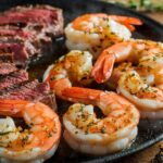 Sizzling Garlic Glazed Steak Shrimp 7 Sizzling garlic glazed steak and shrimp plated with fresh herbs and a garlic glaze drizzle