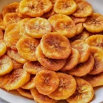Sweet Cinnamon Air Fryer Banana Chips 7 Sweet Cinnamon Air Fryer Banana Chips in a bowl, crispy and golden with a dusting of cinnamon sugar, served as a healthy snack.