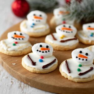 Decorated Melted Snowman Cookies with marshmallow heads, icing, and candy on a sugar cookie base