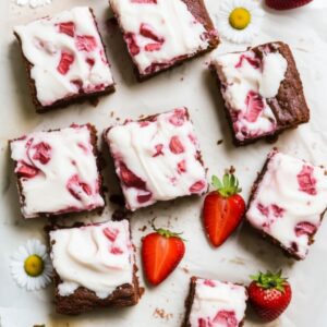 Fudgy strawberry brownies topped with creamy frosting and fresh strawberry slices