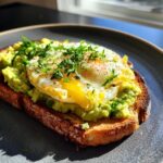 Close-up of a 5-Ingredient Avocado Toast Omelette with a fried egg, avocado, and herbs on toast.