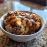 Close-up of a bowl of Caramel Apple Cinnamon Oatmeal Bake, topped with caramel sauce.