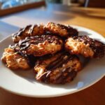 Close-up of Chocolate-Dipped Toffee Almond Cookies on a white plate, drizzled with chocolate.
