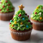 Close-up of a Christmas Tree Cupcake for Kids, decorated with green frosting, colorful candies, and a star topper.