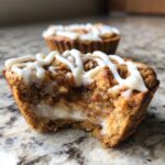 Close-up of a Cinnamon Roll Sugar Cookie Cup with frosting and filling, showing a bite taken out.