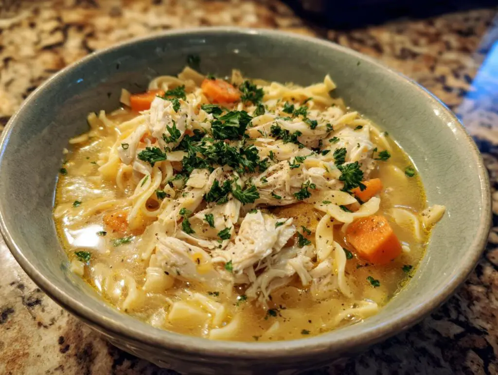 A bowl of Creamy Chicken Noodle Soup with chicken, noodles, and carrots.