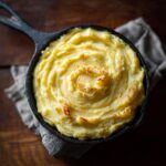 Overhead shot of creamy mashed potatoes in a cast iron skillet, ready to serve.