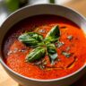 Close-up of a bowl of Creamy Tomato Basil Soup (No Cream!), garnished with fresh basil leaves and olive oil.