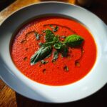 Overhead shot of creamy tomato basil soup (no cream!) garnished with fresh basil and olive oil.
