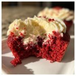 A delicious bite taken out of an Easy Crumbl Red Velvet Cupcake Cookie, revealing the moist red cake and creamy frosting.