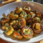 Close-up of Garlic Butter Mushrooms in a white bowl, garnished with herbs and garlic.