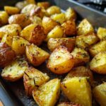 Close-up of crispy, golden Garlic Roast Potatoes seasoned with herbs, ready to eat.
