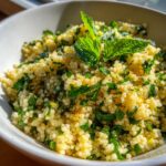 Close-up of a bowl of fresh Herbed Couscous, garnished with mint leaves.
