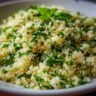 Close-up of a bowl of delicious Herbed Couscous, garnished with fresh herbs.
