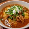 Close-up of a bowl of Instant Pot Chicken Enchilada Soup, topped with sour cream and green onions.