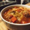 Close-up of a bowl of Keto Cabbage & Sausage Soup with vegetables and sausage.
