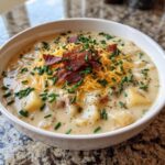 Close-up of a bowl of Loaded Baked Potato Soup, topped with bacon, cheese, and chives.