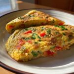 Close-up of a cooked Microwave Mug Omelette with Veggies, served on a plate, with visible vegetables.