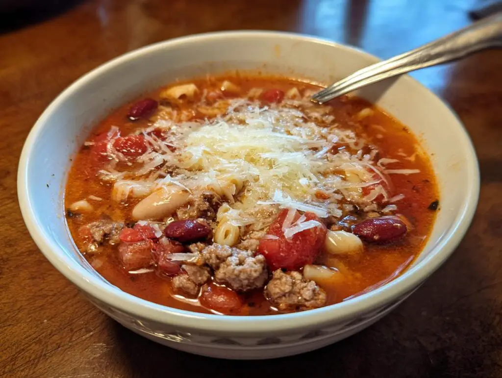A bowl of delicious One-Pot Pasta e Fagioli Soup, topped with cheese, ready to eat.