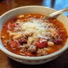 A bowl of delicious One-Pot Pasta e Fagioli Soup, topped with cheese, ready to eat.