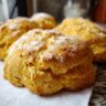 Close-up of golden, fluffy Pumpkin Biscuits dusted with powdered sugar, perfect for fall.