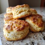 Pile of freshly baked Pumpkin Biscuits on a marble countertop, golden brown and fluffy.