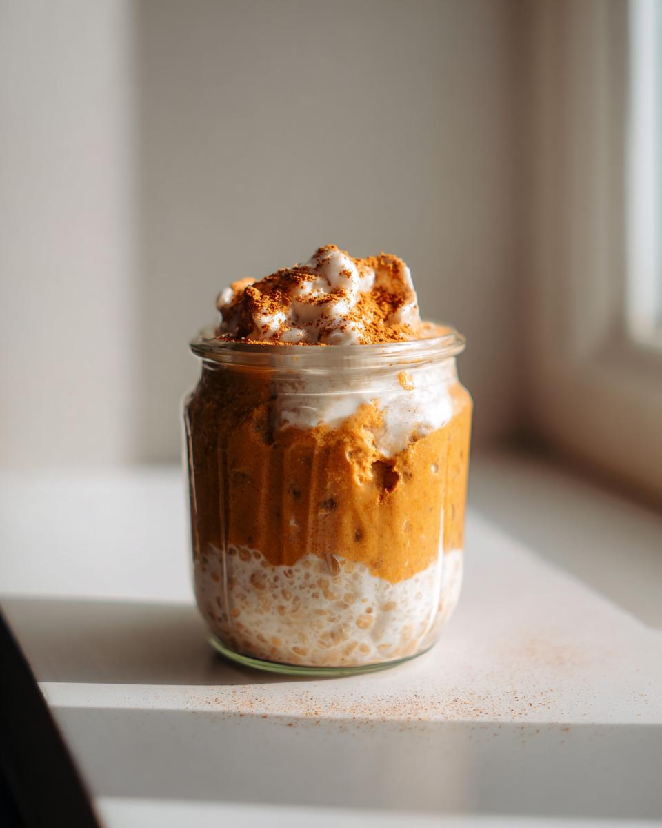 A jar of Pumpkin Spice Latte Overnight Oats, layered with oats and pumpkin spice.