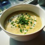 A bowl of creamy Sweet Corn Chowder garnished with chives and a swirl of cream.