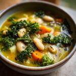 Close-up of a bowl of Tuscan White Bean & Kale Soup with kale, beans, and carrots.