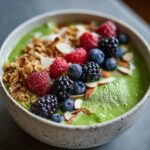 A vibrant Ultra-Green Detox Smoothie Bowl topped with fresh berries, granola, and almond slivers.