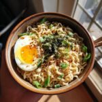 Close-up of an upgraded ramen bowl with a soft-boiled egg, green onions, and seaweed, the Upgraded Ramen Bowl.