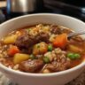 Close-up of a bowl of Beef Barley Guinness Soup with beef, barley, and vegetables.