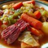 Close-up of a bowl filled with Corned Beef and Cabbage Stew, featuring carrots, cabbage, and potatoes.