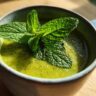 Close-up of a bowl of Green Split Pea Soup with Mint, garnished with fresh mint leaves.
