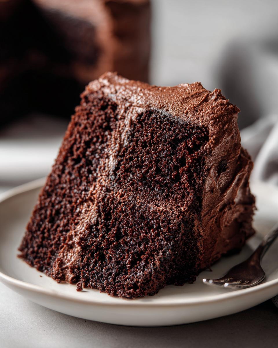Close-up of a slice of Guinness Chocolate Layer Cake on a plate, with chocolate frosting.