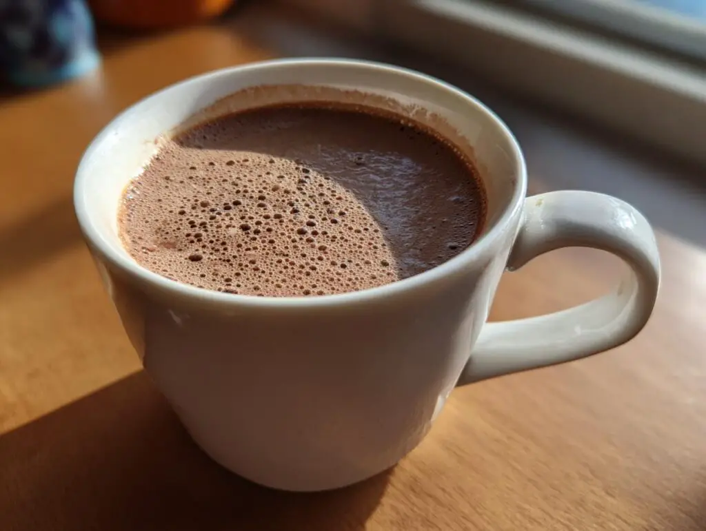 A close-up of a mug filled with the Creamiest Chocolate Recipe, with a foamy top.