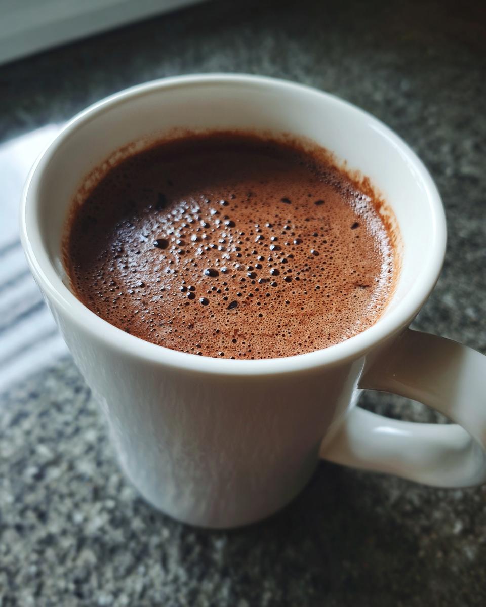 Close-up of a mug filled with the Creamiest Chocolate Recipe, with a foamy top.