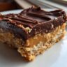 Close-up of a no-bake dessert bar with layers of caramel and chocolate, this dessert requires no baking at all.