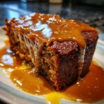 A slice of Biscoff Sticky Toffee Pudding with rich toffee sauce.