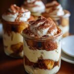 Close-up of Easy Tiramisu Trifle Jars layered with ladyfingers, cream, and cocoa powder.