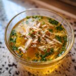 Amazing Fish Broth Cat Recipe: 1 Love Bowl 11 Close-up of a clear glass bowl filled with Fish Broth Cat Recipe, shredded fish, and fresh herbs.