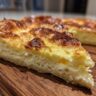 Close-up of a slice of Foolproof Cheese Soufflé, golden brown and fluffy, on a wooden board.