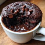 Close-up of a fudgy microwave brownie in a mug with chocolate chips. This is a quick and easy microwave brownie recipe.