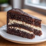 Close-up of a slice of Guinness Chocolate Cake with Irish Buttercream on a white plate.