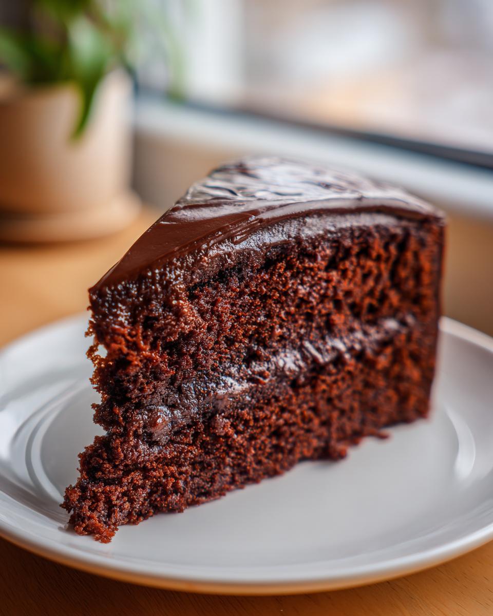 A slice of Guinness Chocolate Cake with Irish Buttercream on a white plate, showing the moist texture.