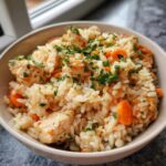 Close-up of a bowl of homemade cat food with chicken, rice, and carrots. The image relates to Budget Homemade Cat Food.