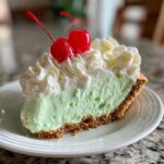 A slice of No-Bake Shamrock Shake Icebox Pie with whipped cream and a cherry on top.