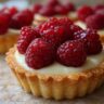 Close-up of a delicious Raspberry Cream Cheese Mini Tart, topped with fresh raspberries.