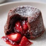 Close-up of a Strawberry Chocolate Lava Cake with a flowing strawberry center and powdered sugar.